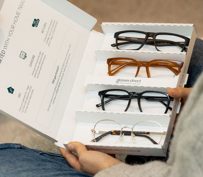 Woman holding her Free home trial box with 4 pairs of frames